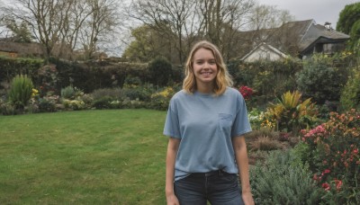 1girl,solo,long hair,looking at viewer,smile,open mouth,blue eyes,blonde hair,shirt,standing,white shirt,flower,short sleeves,cowboy shot,outdoors,teeth,day,pants,medium hair,tree,black pants,grass,blue shirt,denim,t-shirt,building,scenery,jeans,realistic,arms at sides,house,photo background,garden,:d,sky,grin,plant,nature,field