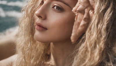 1girl,solo,long hair,looking at viewer,blonde hair,closed mouth,green eyes,blurry,lips,grey eyes,eyelashes,depth of field,blurry background,wavy hair,beach,portrait,close-up,realistic,nose,brown eyes,parted lips,looking up,freckles,curly hair