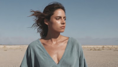 1girl,solo,long hair,breasts,brown hair,shirt,cleavage,brown eyes,medium breasts,closed mouth,collarbone,upper body,small breasts,outdoors,sky,day,blue sky,lips,looking to the side,looking away,wind,messy hair,grey shirt,realistic,nose,sand,looking afar,desert,dark skin,dirty