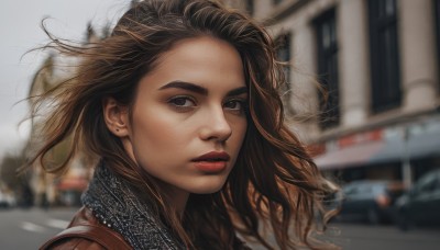 1girl,solo,long hair,looking at viewer,brown hair,brown eyes,jewelry,earrings,outdoors,scarf,blurry,lips,looking to the side,makeup,depth of field,blurry background,lipstick,ground vehicle,wind,messy hair,portrait,motor vehicle,freckles,realistic,nose,red lips,car,stud earrings,parted lips,day,floating hair,building,road,street