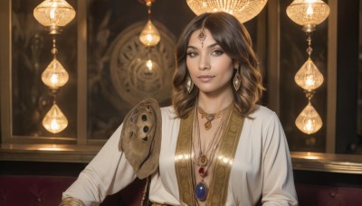 1girl,solo,long hair,breasts,looking at viewer,smile,brown hair,shirt,long sleeves,cleavage,brown eyes,jewelry,medium breasts,sitting,closed mouth,white shirt,upper body,earrings,indoors,dark skin,medium hair,necklace,blurry,bracelet,dark-skinned female,lips,head tilt,blurry background,shoulder armor,gem,pendant,circlet,realistic,forehead jewel,bangs,black hair,parted bangs,eyelashes,makeup,depth of field,couch,pink lips,nose,lamp,red gemstone