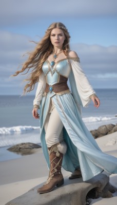 1girl,solo,long hair,breasts,looking at viewer,brown hair,hair ornament,long sleeves,dress,bare shoulders,brown eyes,jewelry,medium breasts,standing,full body,boots,outdoors,sky,day,pants,necklace,blue sky,lips,blue dress,beach,brown footwear,knee boots,gem,rock,realistic,white pants,sand,braid,cloud,water,cape,blurry,fur trim,blurry background,ocean,ring,fur-trimmed boots