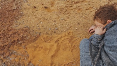 1girl,solo,brown hair,long sleeves,1boy,sitting,jacket,ponytail,male focus,outdoors,pants,animal,traditional media,denim,knees up,jeans,blue pants,on ground,denim jacket,short hair,signature,from above,realistic,photo background,head down