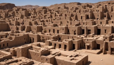 monochrome,outdoors,sky,day,blue sky,no humans,building,scenery,mountain,city,sand,road,cityscape,landscape,desert,rock,ruins,sepia,castle