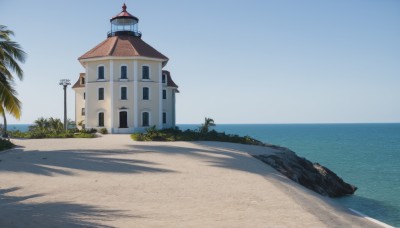 outdoors,sky,day,water,tree,blue sky,no humans,shadow,ocean,beach,grass,plant,building,scenery,rock,sand,palm tree,horizon,bush,lamppost,shore,window,house,lighthouse