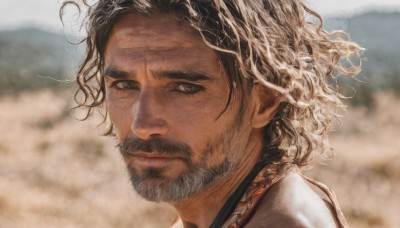 solo,looking at viewer,black hair,1boy,brown eyes,closed mouth,male focus,outdoors,armor,blurry,black eyes,looking to the side,depth of field,blurry background,facial hair,messy hair,portrait,beard,curly hair,realistic,mustache,brown hair,day,dark skin,lips,scar