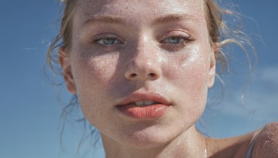 1girl,solo,looking at viewer,short hair,blue eyes,blonde hair,parted lips,sky,teeth,day,lips,portrait,close-up,realistic,nose,blurry,blue sky,grey eyes,eyelashes,floating hair,blue background,wind,freckles,mole on cheek