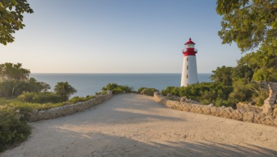 outdoors,sky,day,water,tree,blue sky,no humans,shadow,ocean,beach,grass,plant,scenery,rock,sand,horizon,clock,road,bush,wall,tower,shore,path,cloud,nature,lighthouse