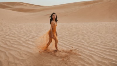 1girl,solo,long hair,breasts,looking at viewer,smile,black hair,dress,bare shoulders,jewelry,medium breasts,standing,closed eyes,outdoors,barefoot,dark skin,water,dark-skinned female,ocean,beach,scenery,walking,sand,desert,footprints,from side,realistic,sepia,waves