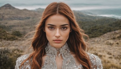 1girl,solo,long hair,looking at viewer,smile,brown hair,dress,brown eyes,closed mouth,upper body,outdoors,sky,day,blurry,lips,blurry background,wavy hair,portrait,forehead,mountain,realistic,straight-on,parted lips,white dress,depth of field,wind