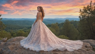 1girl,solo,long hair,looking at viewer,brown hair,gloves,dress,bare shoulders,jewelry,standing,full body,earrings,outdoors,sky,cloud,white dress,tree,see-through,strapless,profile,cloudy sky,nature,scenery,strapless dress,forest,sunset,mountain,wedding dress,long dress,backless dress,mountainous horizon,gown,looking back,rock,backless outfit,realistic,bride,landscape