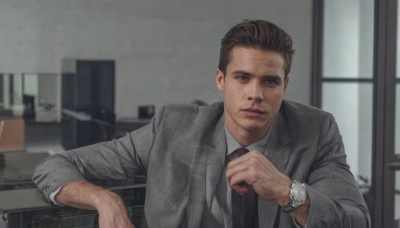 solo,looking at viewer,short hair,brown hair,shirt,long sleeves,1boy,closed mouth,jacket,white shirt,upper body,male focus,necktie,collared shirt,indoors,hand up,blurry,black eyes,blurry background,formal,suit,freckles,watch,realistic,grey jacket,wristwatch,suit jacket,blue eyes,window,depth of field,facial hair,chair,expressionless,stubble,computer,monitor,keyboard (computer),office