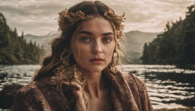 1girl,solo,long hair,looking at viewer,brown hair,black hair,hair ornament,jewelry,upper body,earrings,outdoors,parted lips,sky,day,cloud,hand up,water,blurry,tree,lips,grey eyes,depth of field,blurry background,wavy hair,cloudy sky,portrait,nature,mountain,realistic,nose,head wreath,river,lake,blue eyes,dress,thick eyebrows,forest,overcast