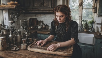 1girl,solo,long hair,brown hair,dress,brown eyes,short sleeves,food,day,indoors,black dress,cup,lips,window,buttons,wavy hair,table,bottle,plant,plate,curly hair,realistic,basket,bread,shelf,kitchen,jar,sink,cabinet,cutting board,closed mouth,apron,fruit,knife,bowl,spoon,glass,cooking,counter,stove