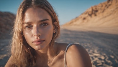 1girl,solo,long hair,looking at viewer,blonde hair,brown hair,bare shoulders,brown eyes,jewelry,collarbone,upper body,earrings,outdoors,parted lips,sky,day,blurry,blue sky,lips,blurry background,portrait,freckles,realistic,nose,desert,depth of field,beach,sunlight,messy hair,close-up,sand,spaghetti strap