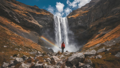 solo, 1boy, standing, outdoors, sky, day, cloud, hood, water, scenery, rock, mountain, wide shot, rainbow, waterfall, cliff