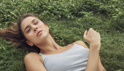 1girl,solo,long hair,breasts,looking at viewer,brown hair,shirt,bare shoulders,brown eyes,closed mouth,upper body,outdoors,lying,sleeveless,on back,lips,half-closed eyes,tank top,grass,plant,realistic,white tank top,short hair,jewelry,collarbone,white shirt,earrings,hand up,signature,sleeveless shirt