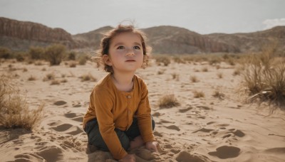 1girl,solo,looking at viewer,short hair,blue eyes,brown hair,shirt,black hair,long sleeves,1boy,closed mouth,male focus,outdoors,shorts,day,pants,blurry,kneeling,blurry background,squatting,child,yellow shirt,realistic,female child,male child,orange shirt,parted lips,sky,aged down,looking up,denim,scenery,rock,sand,dirty