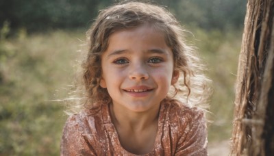 1girl,solo,long hair,looking at viewer,smile,open mouth,brown hair,shirt,upper body,outdoors,teeth,day,blurry,tree,lips,grey eyes,depth of field,blurry background,messy hair,portrait,curly hair,realistic,blue eyes,sunlight,nature